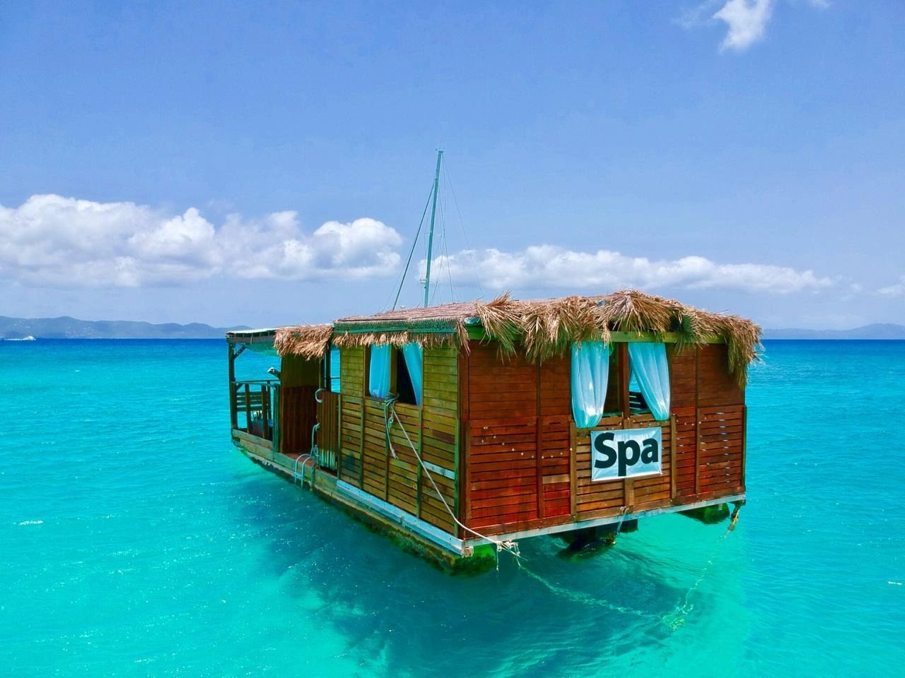 Tropical floating spa hut on clear blue water